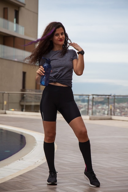 Young Fit woman drinking water with a bottle in her hands Doing sport outside concept