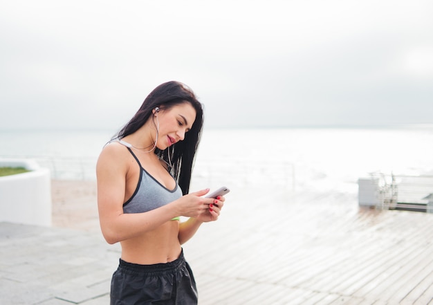 Young fit woman listening to music with earphones