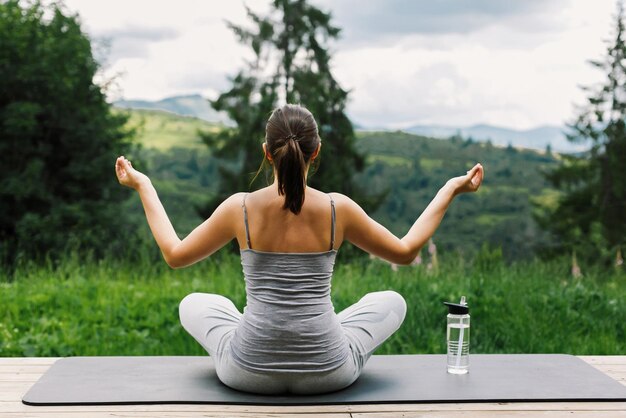 Young fit woman practising yoga and meditation on background of sunny mountains healthy lifestyle