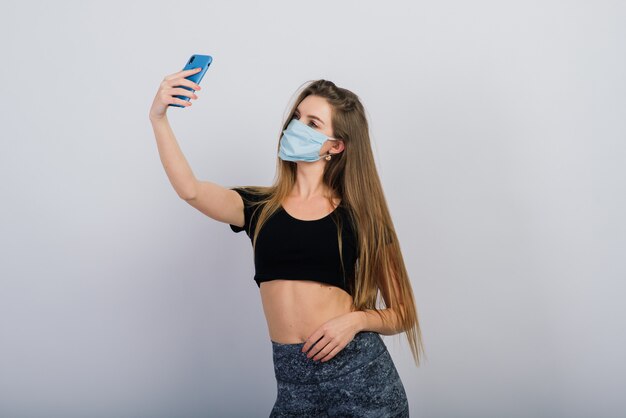 Young fit woman with a smartphone and a face mask