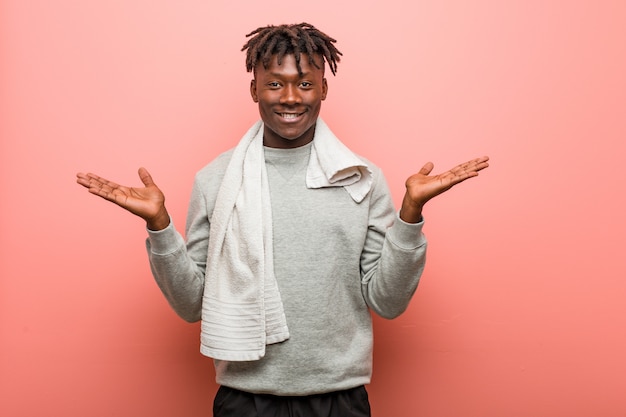 Young fitness african black man makes scale with arms, feels happy and confident.