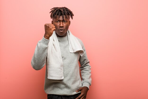 Young fitness african black man showing fist with aggressive facial expression.