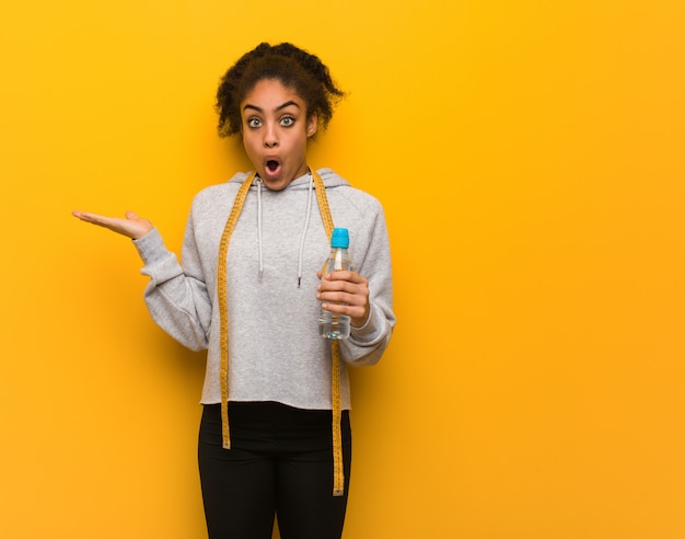 Young fitness black woman holding something on palm hand.Holding a water bottle.