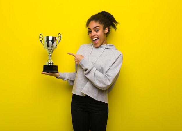 Young fitness black woman holding something with hand. Holding a trophy.