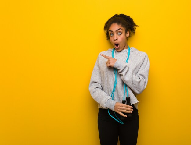 Photo young fitness black woman pointing to the side. holding a jump rope.