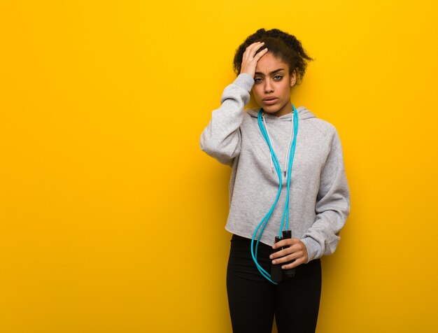 Young fitness black woman tired and very sleepy. Holding a jump rope.