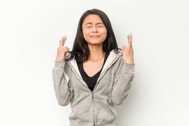 Young fitness chinese woman crossing fingers for having luck