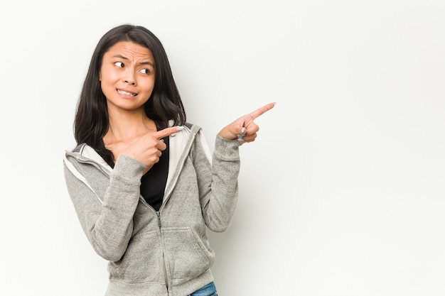 コピースペースを人差し指で指しているショックを受けた若いフィットネス中国の女性。