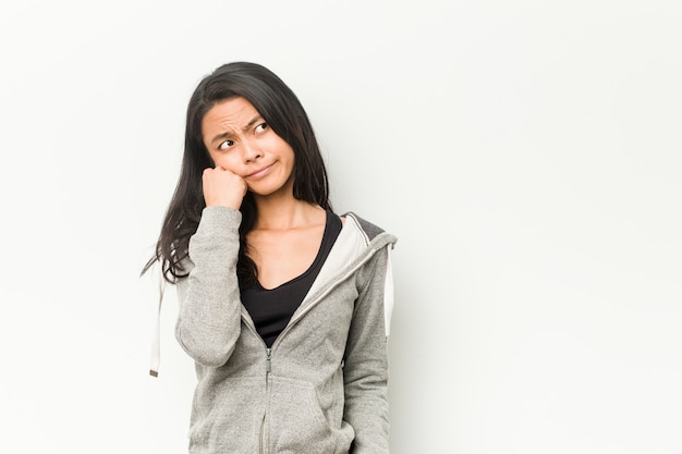 Young fitness chinese woman who feels sad and pensive, looking at copy space.