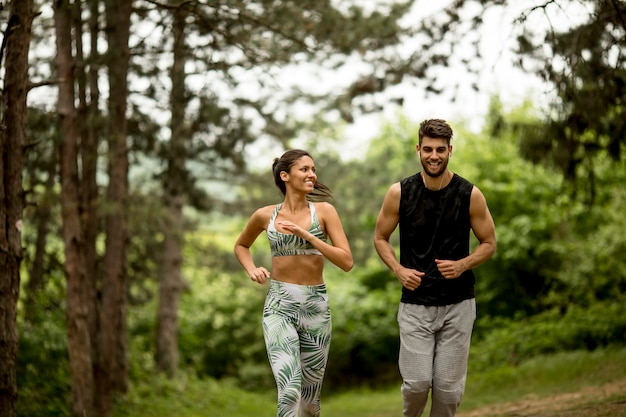 Young fitness couple running at the forest trail