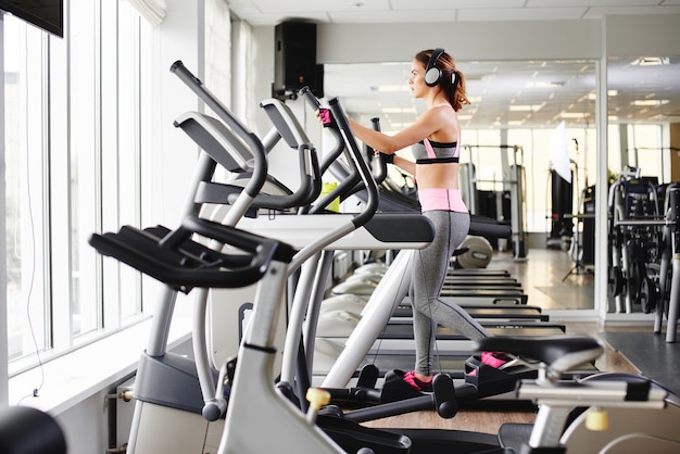 Young fitness girl doing exercises on the machine at the gym