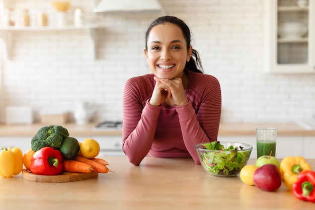 Young fitness lady posing at dining table in kitchen interior