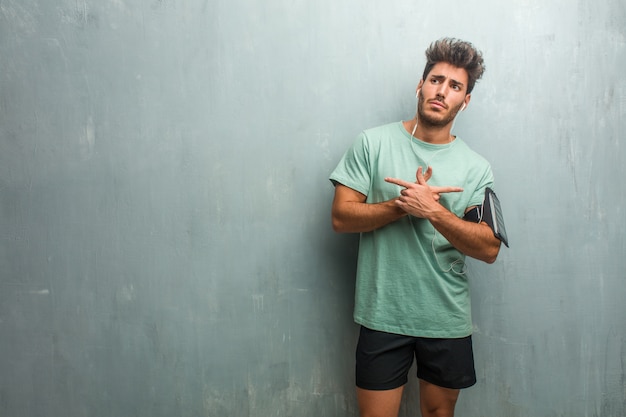 Young fitness man against a grunge wall confused and doubtful, decide between two options