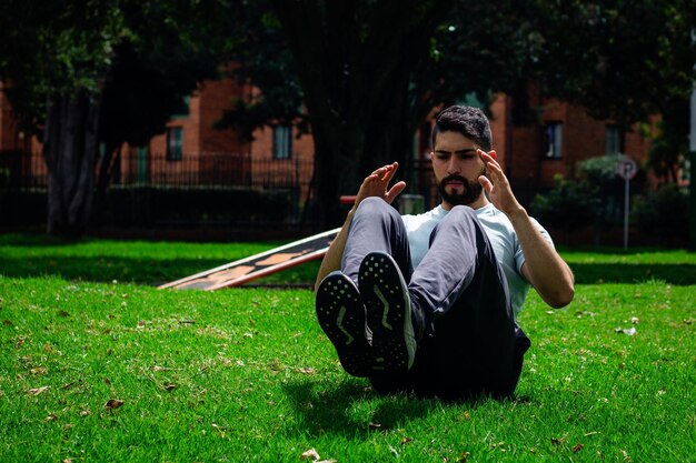 Photo young fitness man doing situps working out in a park in the city outdoors