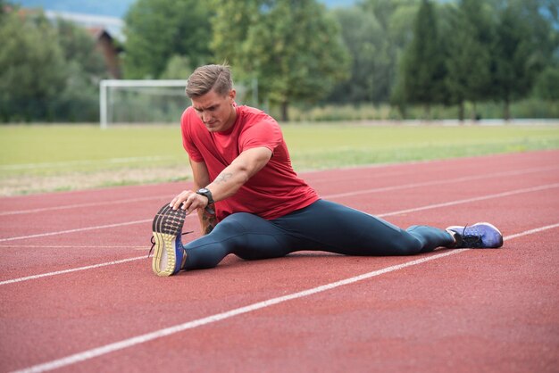 走る前に足を伸ばす若いフィットネス男ランナー