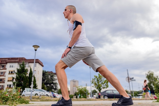 Young fitness man runner stretching legs before running