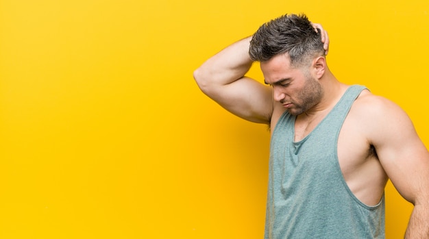 Young fitness man  touching back of head, thinking and making a choice