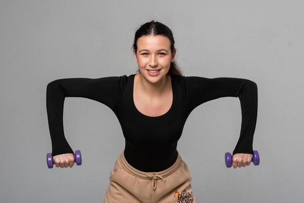 Young fitness model trains with dumbbells