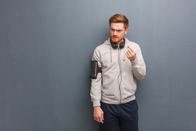 Young fitness redhead man doing a gesture of need