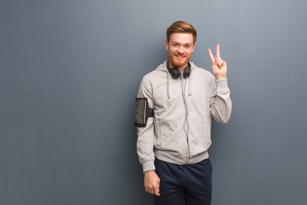 Young fitness redhead man showing number two