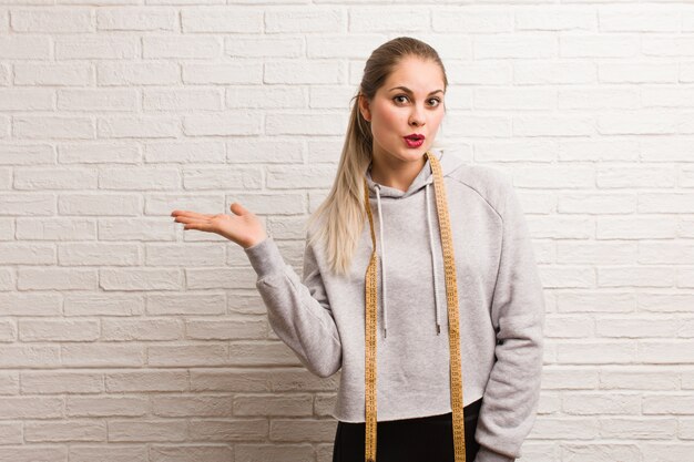 Young fitness russian woman holding a measure tape