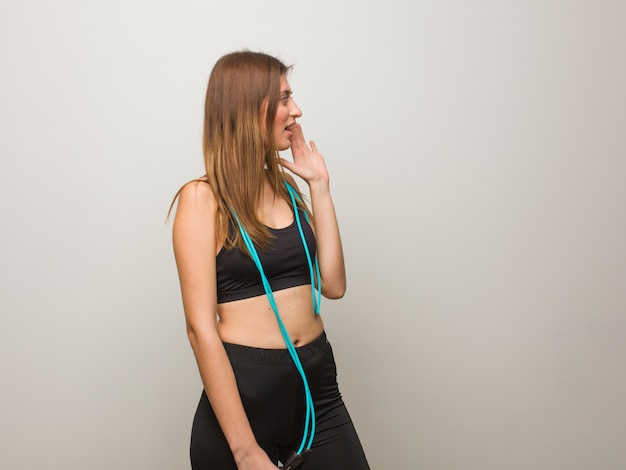 Photo young fitness russian woman whispering gossip undertone. holding a jump rope.
