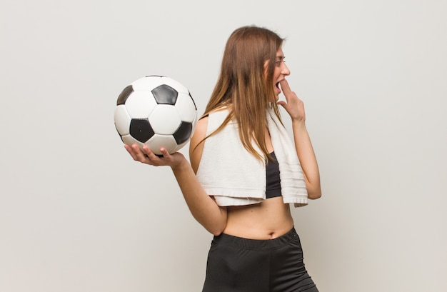 Photo young fitness russian woman whispering gossip undertone. holding a soccer ball.