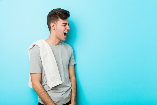 Young fitness teenager man shouting towards a copy space