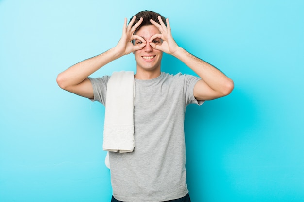 Young fitness teenager man showing okay sign over eyes