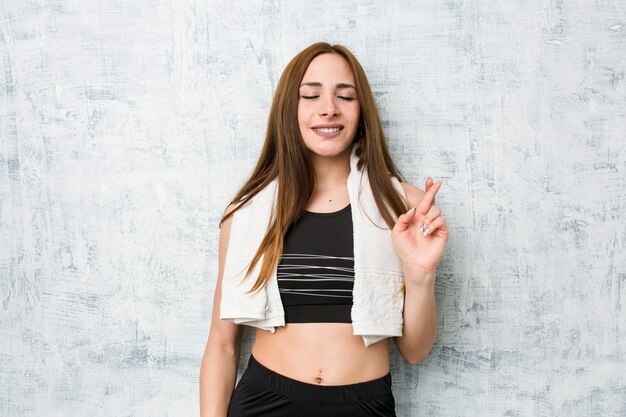 Young fitness woman crossing fingers for having luck