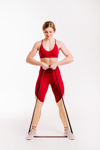 Young fitness woman doing exercises with sport fitness rubber bands on white background