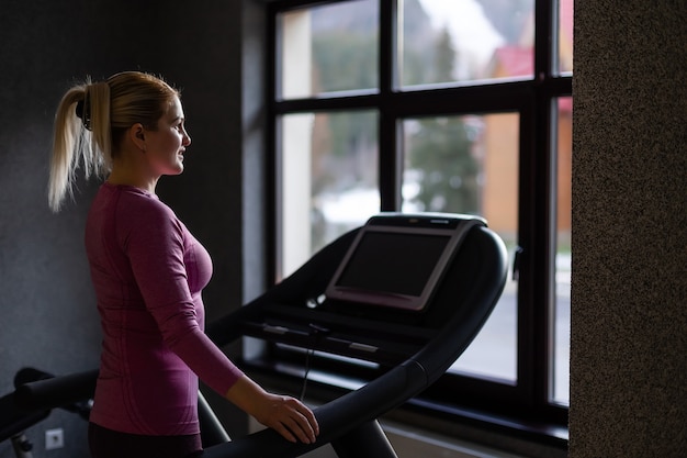 young fitness woman execute exercise with exercise-machine in gym, horizontal photo