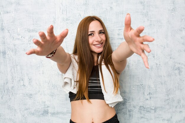 Foto la giovane donna di forma fisica si sente sicura dando un abbraccio alla macchina fotografica.