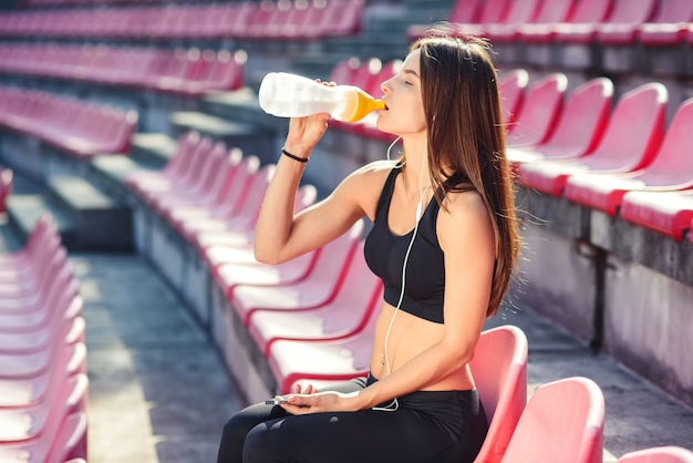 Young fitness woman listening to music on smartphone