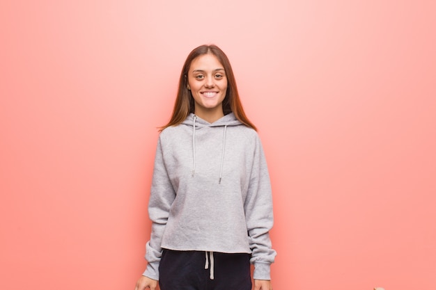 Young fitness woman on pink wall