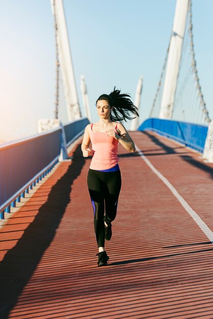 街の橋を走っている若いフィットネス女性ランナー。スポーツコンセプト。