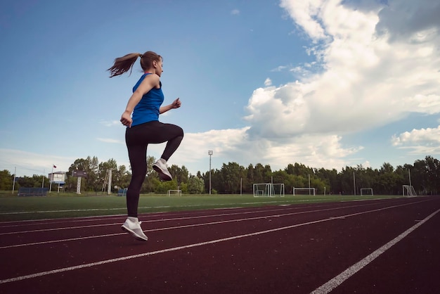 Молодая фитнес-женщина бегает по стадиону Легкая атлетика на стадионе
