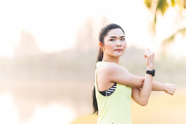 Young fitness woman runner stretching before run on The park