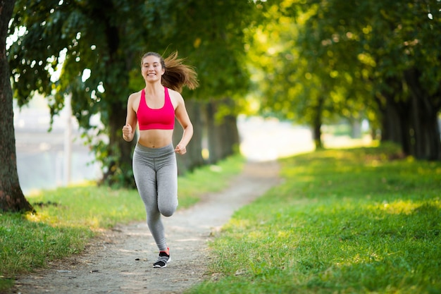 Young fitness woman running around in the park 