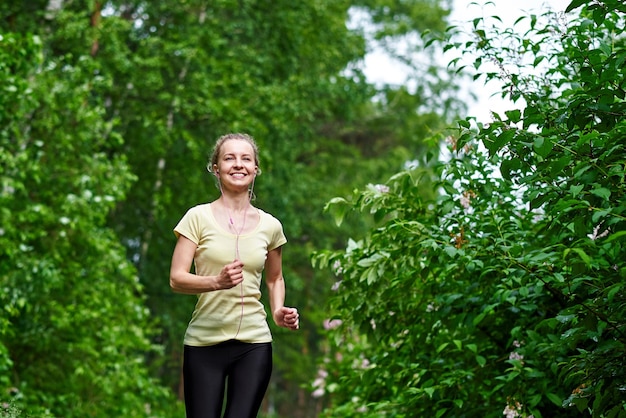 Young fitness woman running at forest trail