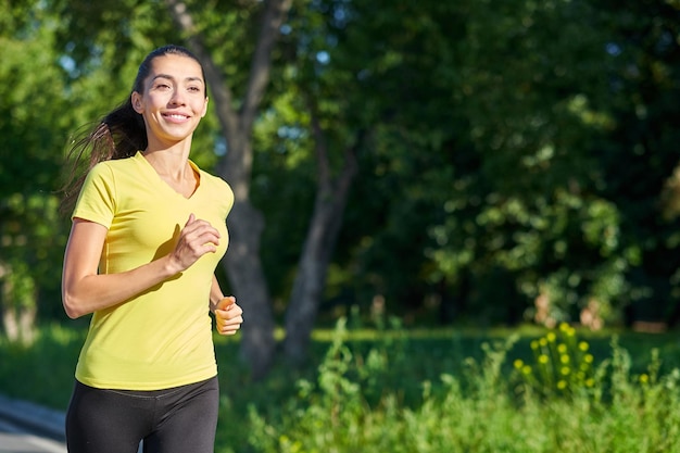 Young fitness woman running at forest trail