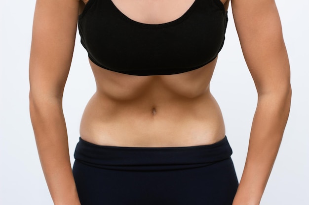 A young fitness woman in a sports black closes does a vacuum abdominal abdomen muscles