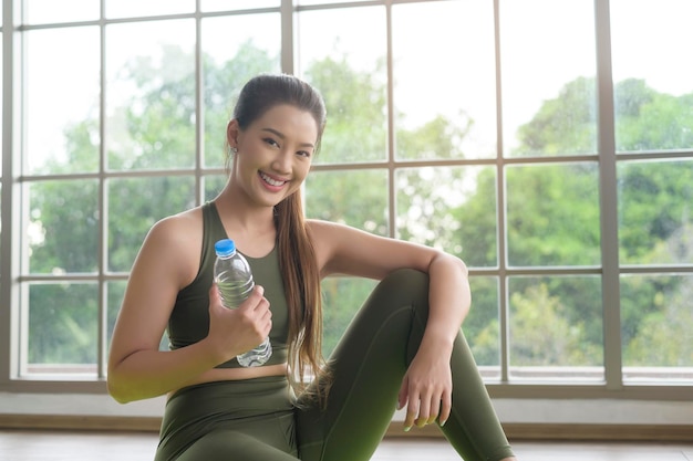 Giovane donna fitness in abbigliamento sportivo acqua potabile dopo l'esercizio a casa salute e stili di vita