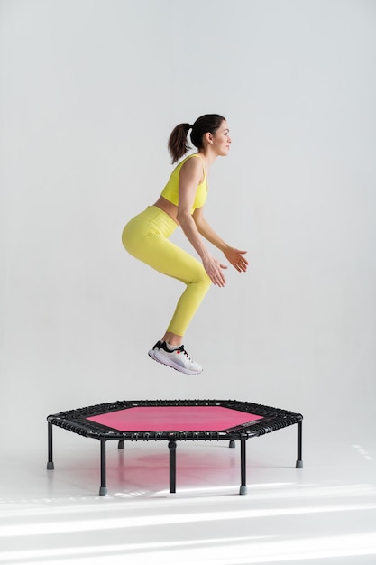 Молодая фитнес-женщина в спортивной одежде прыгает на спортивном батуте