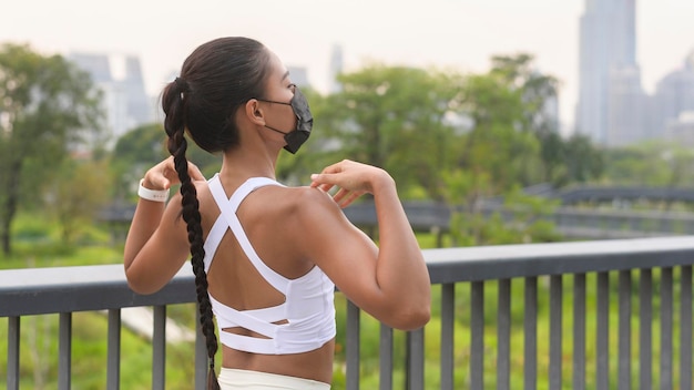 Giovane donna fitness in abbigliamento sportivo che indossa la maschera durante l'esercizio in città