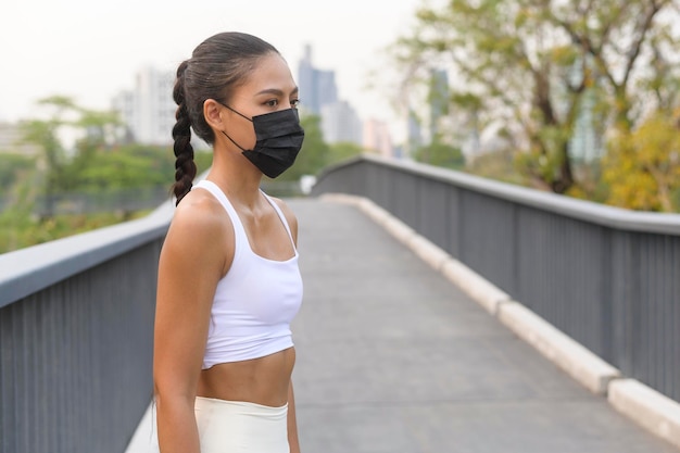 Photo young fitness woman in sportswear taking face mask in while exercise in city