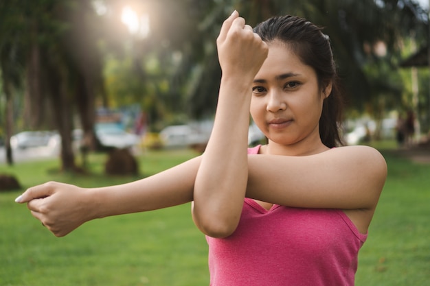 Foto giovane donna di forma fisica che allunga braccio, tricep e spalle prima di esercizio all'aperto nel parco.