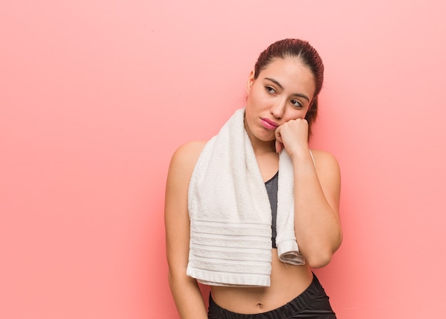 Young fitness woman thinking of something, looking to the side