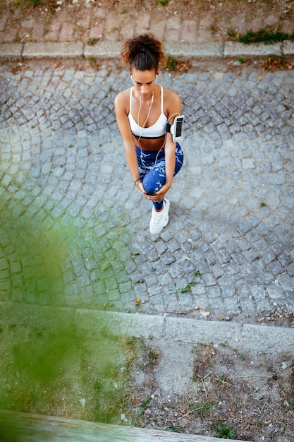 Giovane donna fitness con le cuffie che fanno esercizio di stretching.