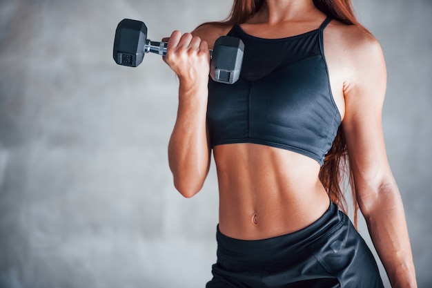 Young fitness woman with slim type of body and in black sportive clothes is in the gym.